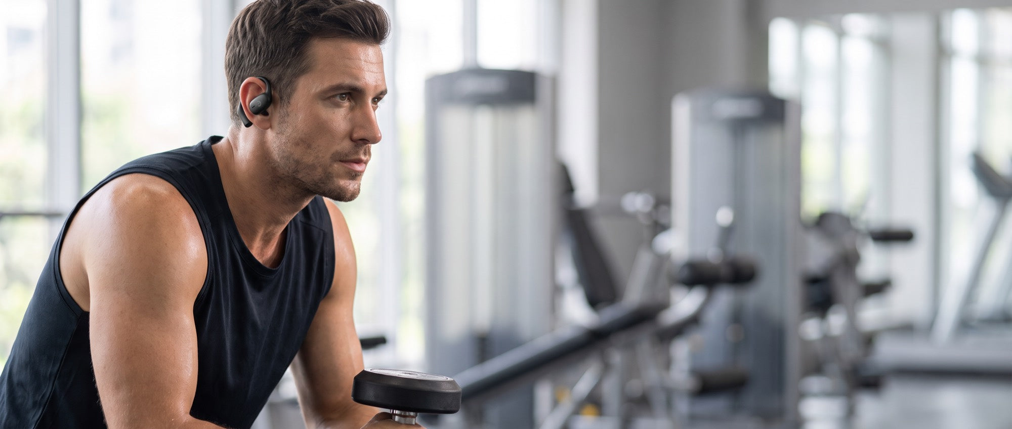 A lifter resting between sets wearing the Essential Open Earbuds, ear canal open