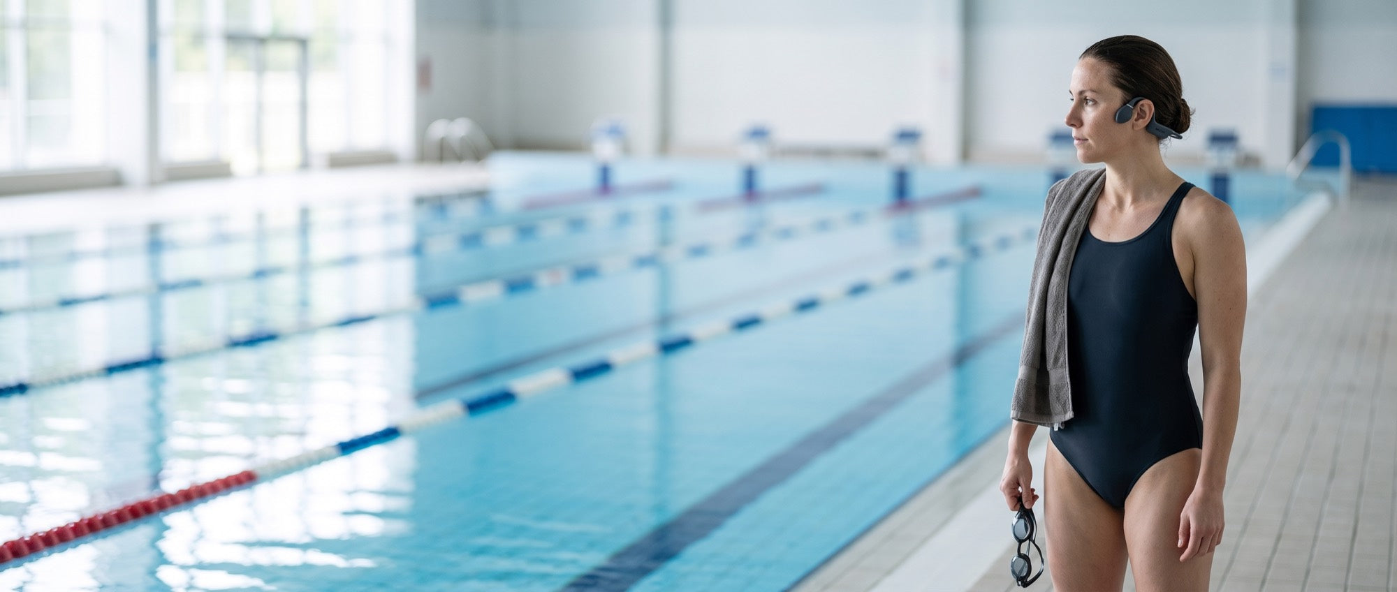 A swimmer poolside, dry on the deck, wearing the Bone Conduction Headphones