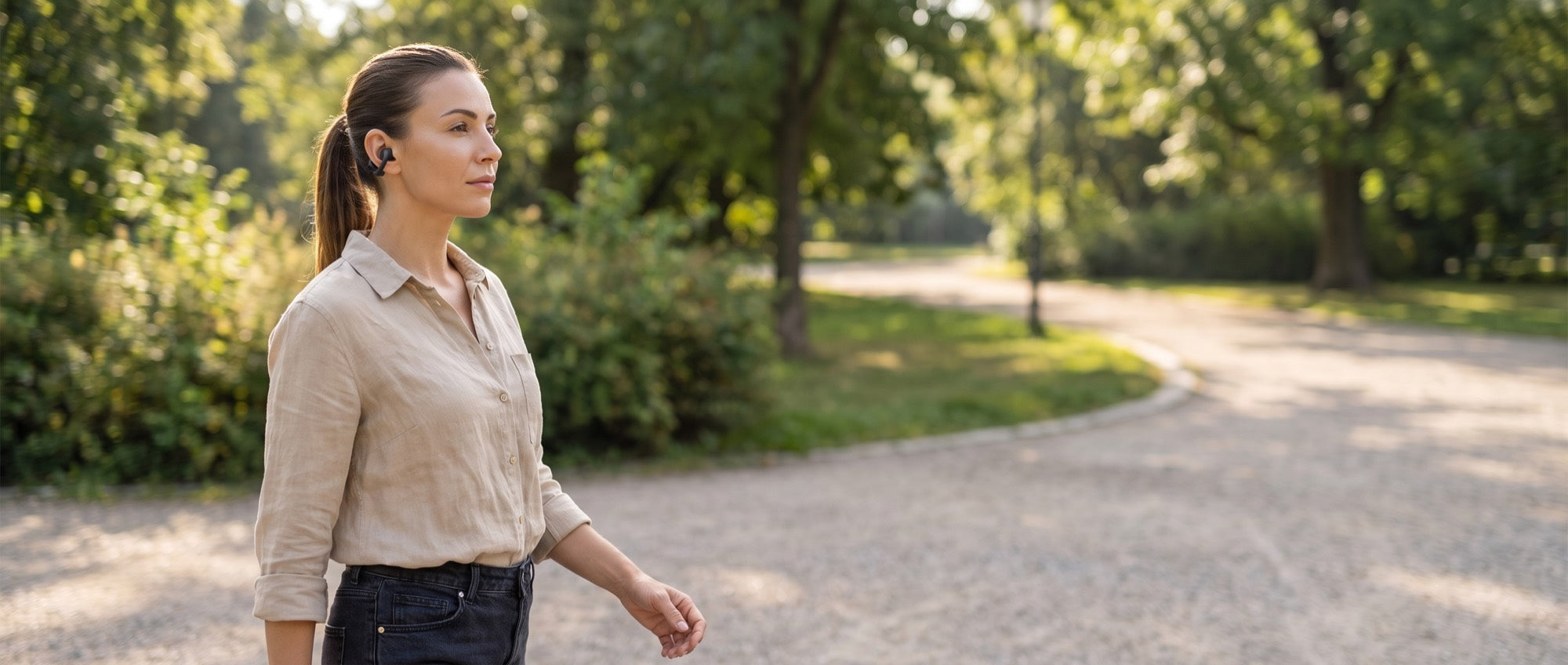 A walker in a city park wearing the Everyday Clip Earbuds, ear canal open